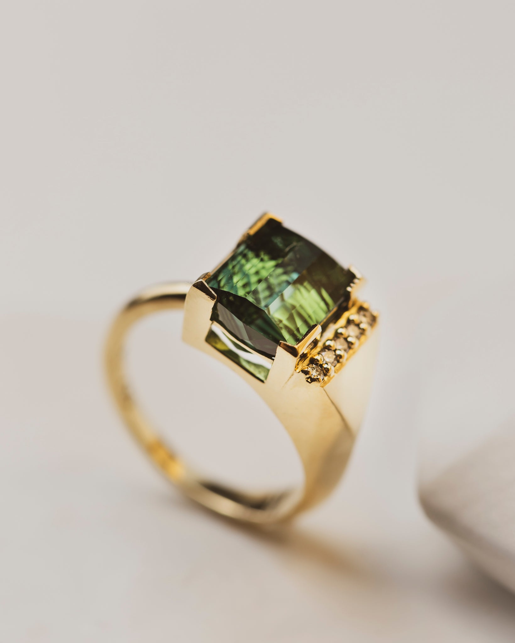 Symmetry and asymmetry play beautifully together in this art deco themed tourmaline ring. The 18K band is a thick knife edge under white diamonds on one side, meeting the other side of the parti4.6 carat partial bezel set Tourmaline Ring with five 1.5mm white diamonds