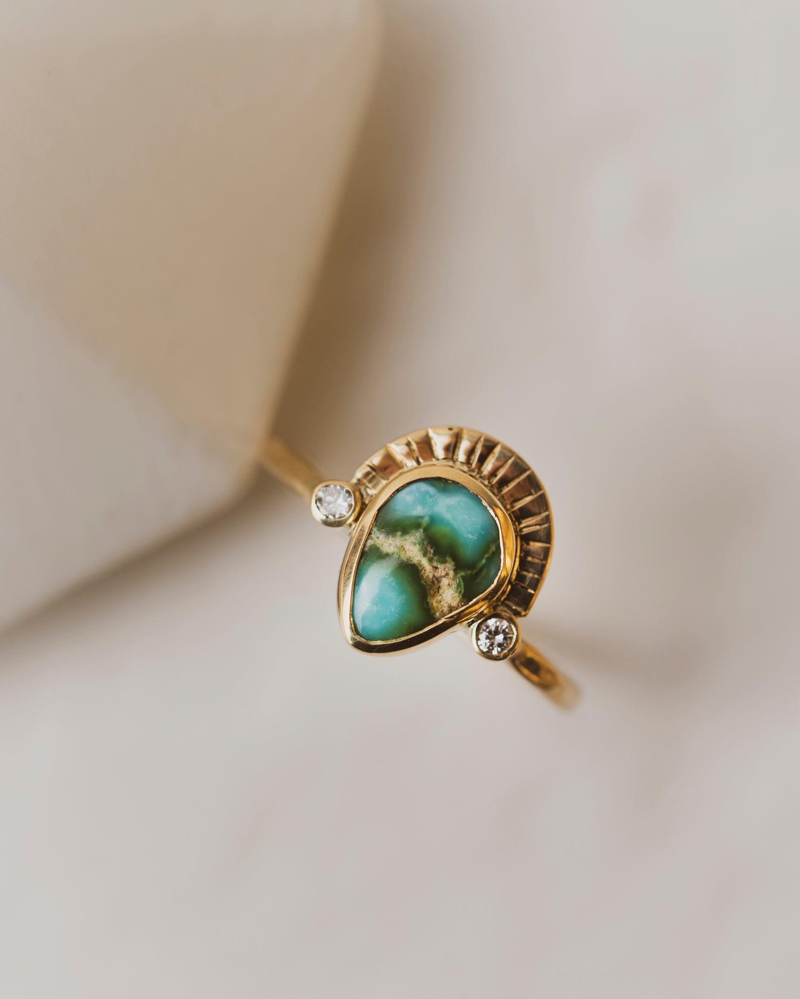 Sonoran Gold Turquoise is bezel set between two 2mm white diamonds on a shield of 18K yellow gold
